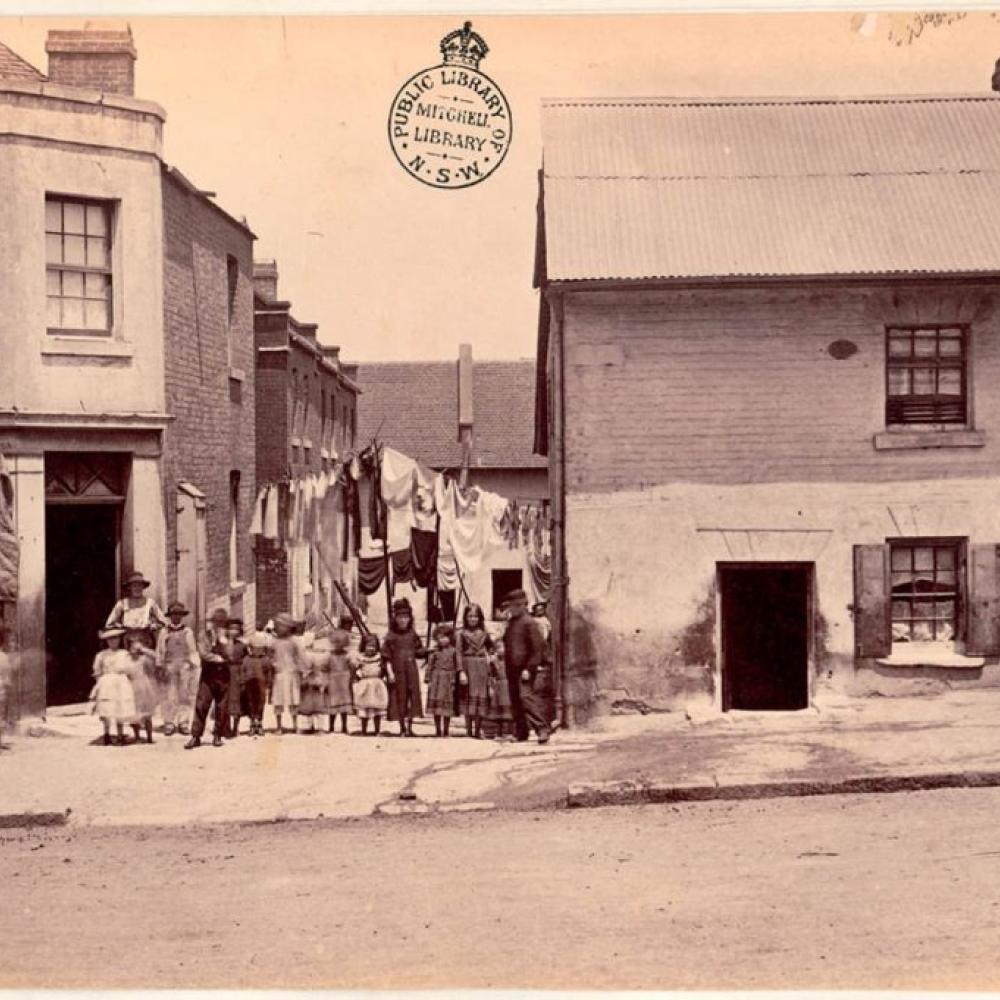 Old black and white photo with people posing between homes