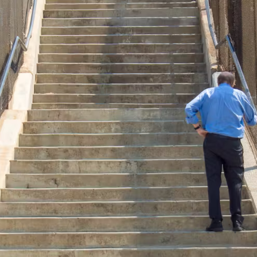 Old man struggling to climb a flight of stairs